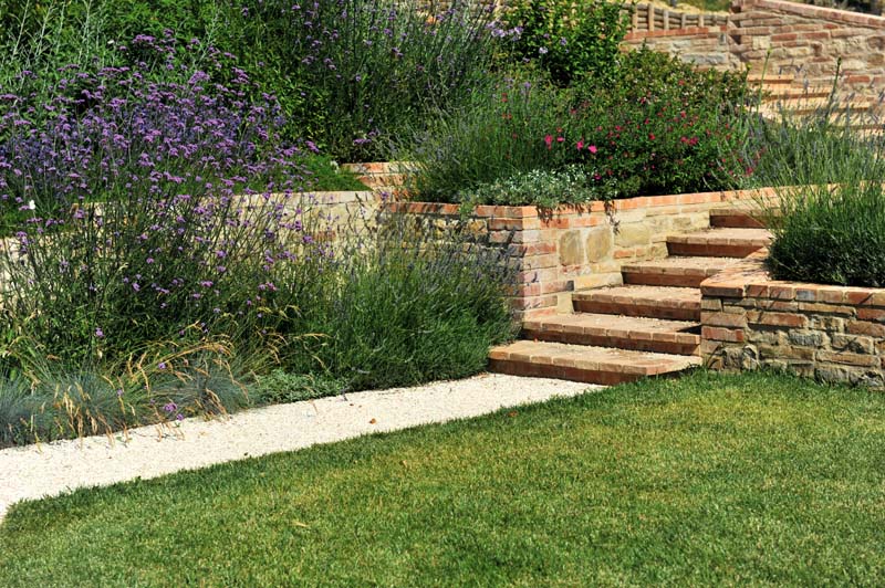 Il giardino è affollato di bordure miste di graminacee e piccoli arbusti