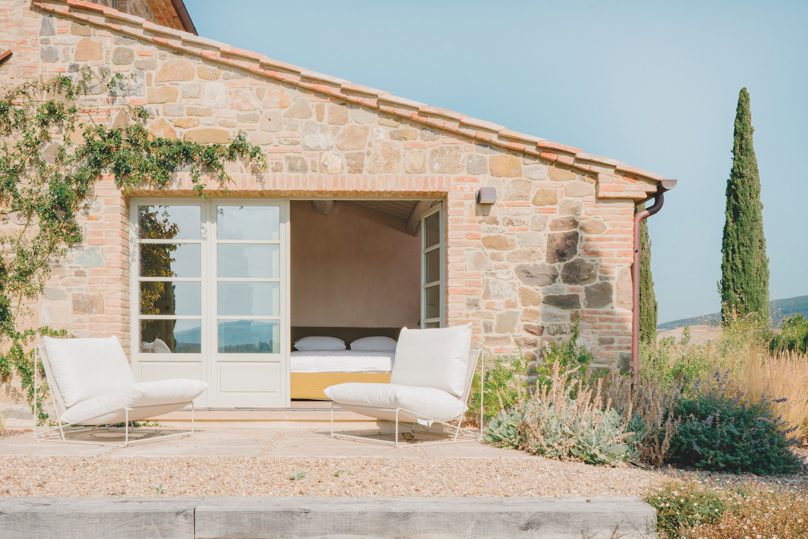 Una vista del casale in Val d'Orcia recuperato: una delle camera affaccia direttamente sull'esterno con una zona conversazione e relax outdoor.