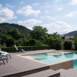 Una piscina con solarium con un lato realizzato in vetro acrilico