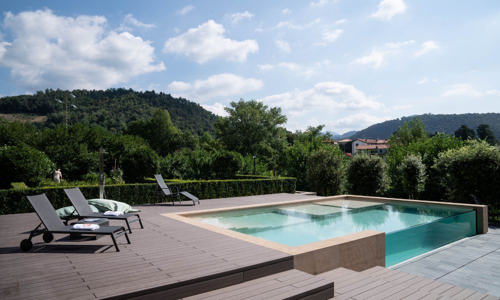 Una piscina con solarium con un lato realizzato in vetro acrilico