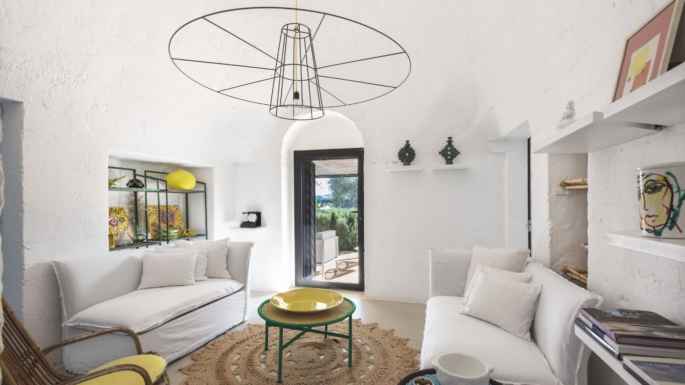 Il living del trullo con piscina in Puglia, arredato con i divani in lino realizzati su disegno da artigiani locali, come i mobili
a muro in lamiera stirata.
